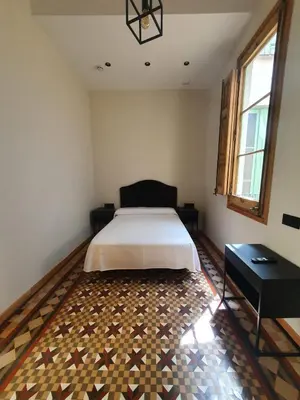 a bedroom with a bed and a table and a window at Hostal Lausanne in Barcelona