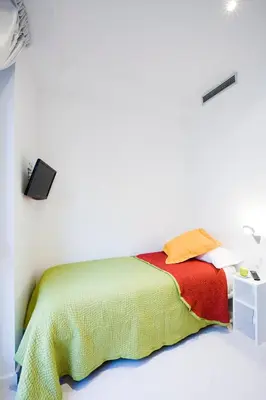 a white room with a bed with a colorful blanket at Live & Dream in Barcelona