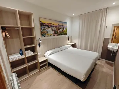 a bedroom with a large white bed and shelves at Hostal BESTPRICE Barcelona Stadium in Barcelona