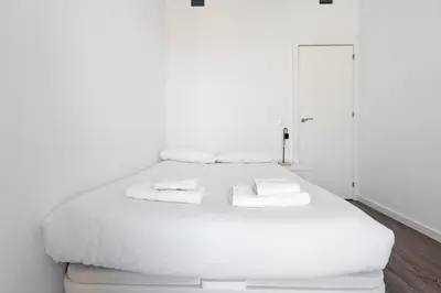 a white bed with white sheets and towels on it at Camp Nou Apartment in Hospitalet de Llobregat