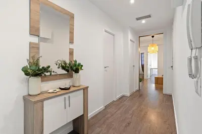 a hallway with white walls and a console table with plants at Camp Nou Apartment in Hospitalet de Llobregat