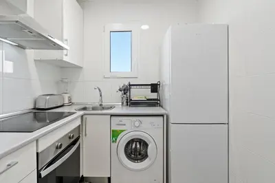a white kitchen with a washing machine in it at Camp Nou Apartment in Hospitalet de Llobregat