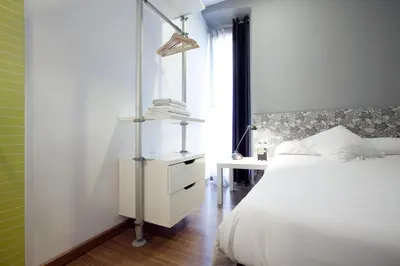 a bedroom with a white bed and a desk at Hostal Nitzs Bcn in Barcelona