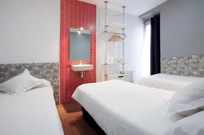 a bedroom with two beds and a sink and a mirror at Hostal Nitzs Bcn in Barcelona