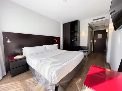 a bedroom with a large white bed and a red table at SM Hotel Sant Antoni in Barcelona