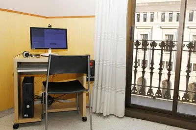 a desk with a computer and a chair next to a window at Hostal Nuevo Colon in Barcelona