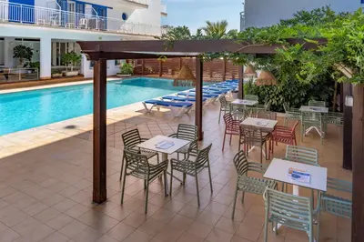 a patio with tables and chairs next to a pool at Hotel Sorrabona in Pineda de Mar
