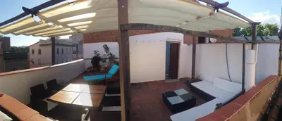 an outdoor patio with awning and tables and chairs on a roof at LG Big Flat Barcelona in Badalona