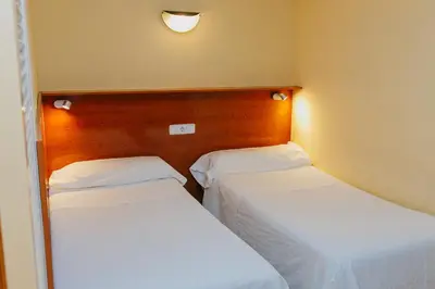 two beds in a room with white sheets at Aparthotel Bertrán in Barcelona