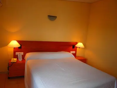 a bedroom with a white bed and two lamps at Aparthotel Bertrán in Barcelona