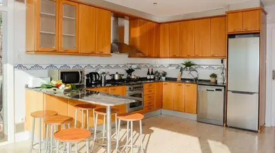 a kitchen with wooden cabinets and a island with stools at Villa Med A 2 kilometros andando de la playa, del puerto de Aguadoç y a 4 del centro de Sitges Muy Soleada todo el dia Capacidad superior a 16 personas NO REQUIERE COCHE in Sitges