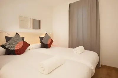 two beds in a room with white sheets and pillows at Canela Homes BARCELONA MACBA in Barcelona