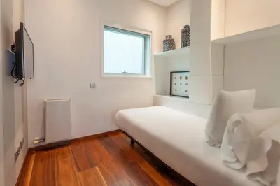 a white bedroom with a bed and a window at Suites Avenue in Barcelona