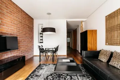 a living room with a black couch and a brick wall at Suites Avenue in Barcelona