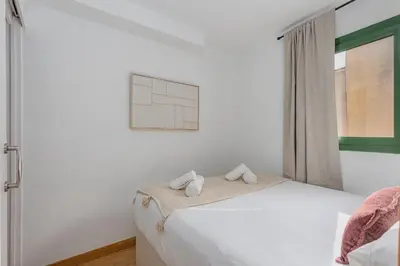 a white bedroom with a bed and a window at Ola Living Vidreria in Barcelona