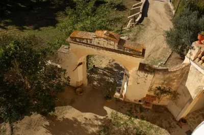 an old building with an arch in a dirt road at Can Rovira - Stunning Neoclassical Mansion, Just 20 min drive from Barcelona City Center, Ideal for groups and families in Alella