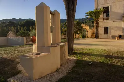 a stone box sitting in the grass next to a building at Can Rovira - Stunning Neoclassical Mansion, Just 20 min drive from Barcelona City Center, Ideal for groups and families in Alella