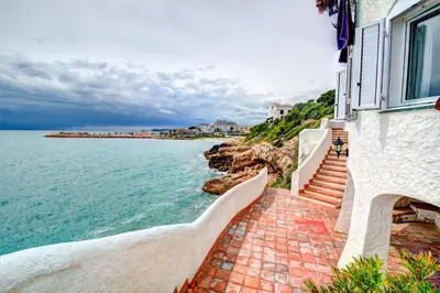 a house with stairs next to the ocean at The Magic Sea Front by Hello Homes Sitges in Sitges