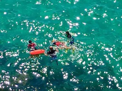 a group of people swimming in the water at The Magic Sea Front by Hello Homes Sitges in Sitges