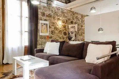 a living room with a couch and a stone wall at Loft en Gràcia ArchsenseApartments in Barcelona
