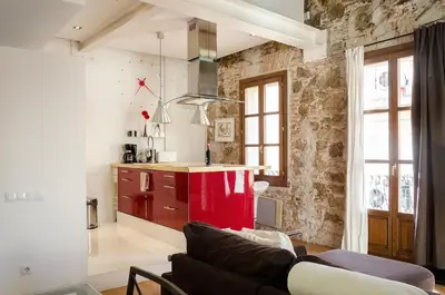 a living room with a couch and a red kitchen at Loft en Gràcia ArchsenseApartments in Barcelona