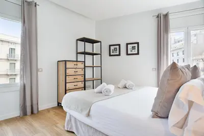 a white bedroom with two beds and a window at Amister Apartments in Barcelona