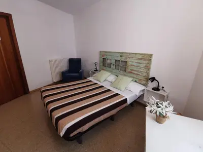 a bedroom with a large bed with a wooden headboard at Mucha Masia Hostel Rural Urba in El Prat de Llobregat