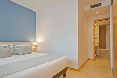 a bedroom with a white bed and a bathroom at Lugaris Rambla Apartments in Barcelona