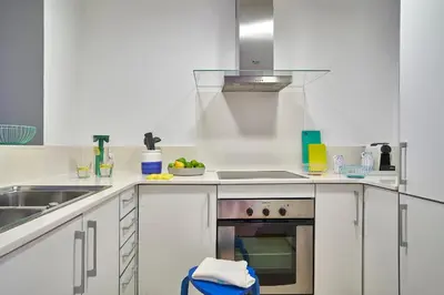 a kitchen with white cabinets and a stove top oven at Lugaris Rambla Apartments in Barcelona