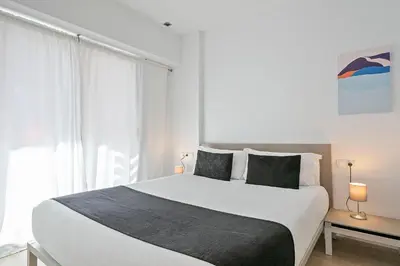 a bedroom with a large white bed and a window at Lugaris Rambla Apartments in Barcelona