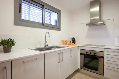 a white kitchen with a sink and a window at Lugaris Rambla Apartments in Barcelona