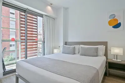 a white bedroom with a large bed and a window at Lugaris Rambla Apartments in Barcelona
