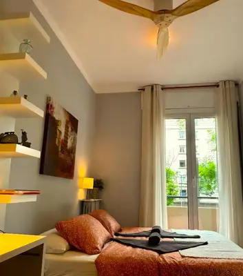 a bedroom with a bed with a ceiling fan and a window at Gracia Apartment in Barcelona