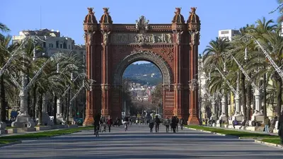 an arch in the middle of a street with palm trees at Gracia Apartment in Barcelona