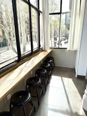 a row of stools in a room with windows at Hip Karma Hostel in Barcelona
