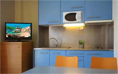 a kitchen with blue cabinets and a sink and a microwave at AQUA Hotel Nostre Mar Apartments in Pineda de Mar