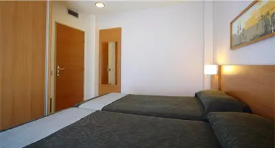 a bedroom with a bed and a wooden door at AQUA Hotel Nostre Mar Apartments in Pineda de Mar