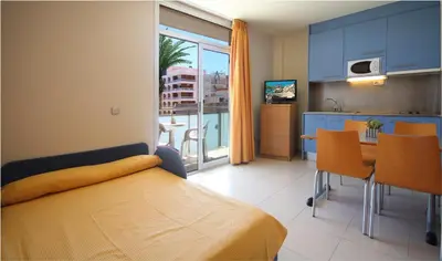 a bedroom with a bed and a kitchen with a table at AQUA Hotel Nostre Mar Apartments in Pineda de Mar