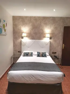 a bedroom with a large white bed with two pillows at Hotel Lloret Ramblas in Barcelona