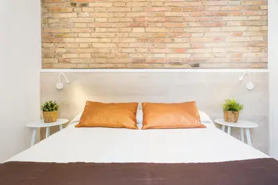 a bedroom with a white bed and a brick wall at BcnStop Sagrada Familia in Barcelona