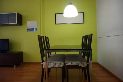 a dining room table and chairs with a green wall at ApartEasy - Montjuïc & Fira in Barcelona