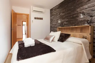 a bedroom with a large white bed with a brick wall at Apartment Beach Front Canet in Canet de Mar