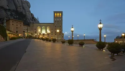 a large building with a clock tower on a street at Hotel Abat Cisneros Montserrat in Montserrat