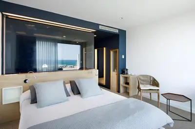 a bedroom with a bed and a window and a chair at Hotel Boutique dONNA in Castelldefels