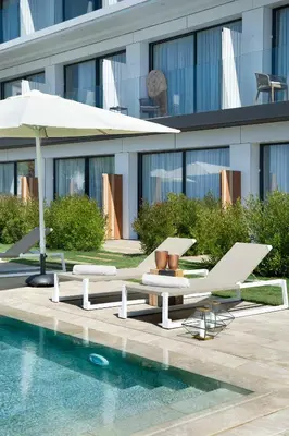a pool with two lounge chairs and an umbrella at Hotel Boutique dONNA in Castelldefels