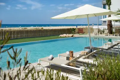 a swimming pool with lounge chairs and an umbrella at Hotel Boutique dONNA in Castelldefels