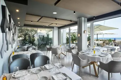a restaurant with white tables and chairs and windows at Hotel Boutique dONNA in Castelldefels