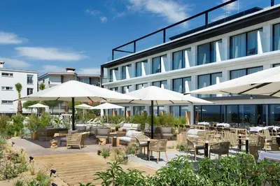 a patio with tables and chairs and umbrellas in front of a building at Hotel Boutique dONNA in Castelldefels