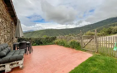 a patio with a table and chairs and a fence at Can Rovira de Fogars in Montseny