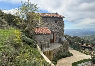 a stone house on the side of a hill at Can Rovira de Fogars in Montseny